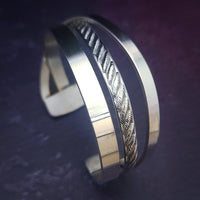 Experience the sophistication of our CROSSOVER Cuff No. 3, featuring smooth sterling silver bands intricately woven to form a unique bracelet. The traditional rope design adds dimension and flair.
Pair it with our collars to make a bold statement.