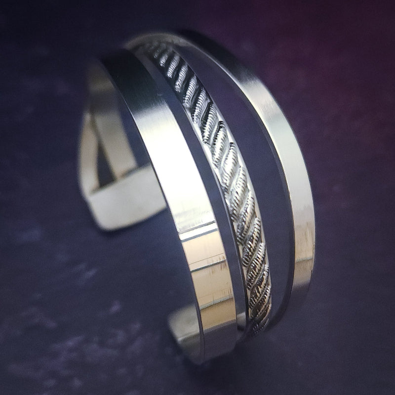 Experience the sophistication of our CROSSOVER Cuff No. 3, featuring smooth sterling silver bands intricately woven to form a unique bracelet. The traditional rope design adds dimension and flair.
Pair it with our collars to make a bold statement.