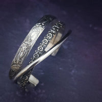 Discover the elegance of our CROSSOVER Cuff No. 4 with its trio of intricate sterling silver patterns that seamlessly intertwine to create a one-of-a-kind bracelet. Pair it with our collars for the ultimate statement piece. The Soft and Sweet and Lokelani Rose patterns are beautifully crafted with a polished sterling wire.