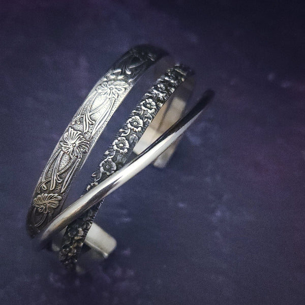 Discover the elegance of our CROSSOVER Cuff No. 4 with its trio of intricate sterling silver patterns that seamlessly intertwine to create a one-of-a-kind bracelet. Pair it with our collars for the ultimate statement piece. The Soft and Sweet and Lokelani Rose patterns are beautifully crafted with a polished sterling wire.