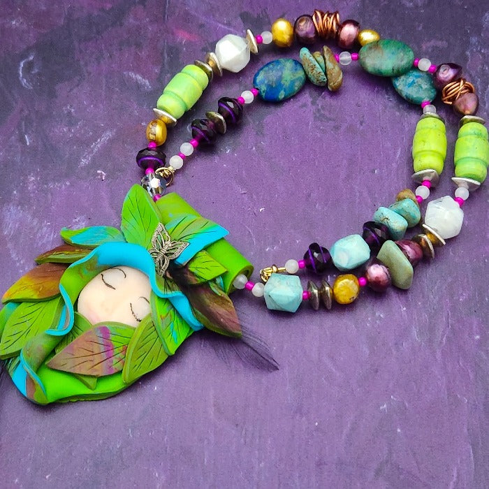 FOREST FAIRIES are ONE OF A KIND Artisan Necklaces. A sweet little fairy is caught napping in her nest of leaves. Each is a one of a kind piece of wearable art with her own unique look and personality. The faces are hand-painted and then surrounded by hand-cut leaves and collected beads, gemstones and sculpted treasures. By Studio Navarri