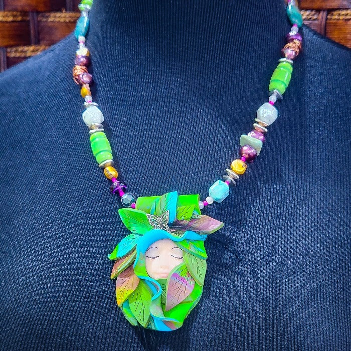 FOREST FAIRIES are ONE OF A KIND Artisan Necklaces. A sweet little fairy is caught napping in her nest of leaves. Each is a one of a kind piece of wearable art with her own unique look and personality. The faces are hand-painted and then surrounded by hand-cut leaves and collected beads, gemstones and sculpted treasures. By Studio Navarri