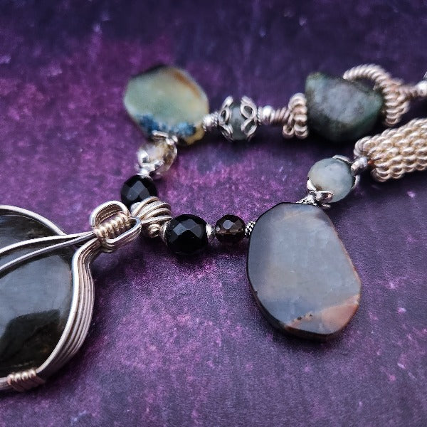 We all have a light within, an inner glow that others may see when they connect with our spirit. The shimmer and glow of this Labradorite Cabochon reminds me of this. This asymmetrical collar necklace is a testament to artisan craftsmanship and design. The Labradorite Cabochon is encased in a Wire Wrapped setting with a beautifully fluid look, and sterling silver coiled pieces add a unique look.