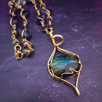 We all have a light within, an inner glow that others may see when they connect with our spirit. The shimmer and glow of this Labradorite Cabochon reminds me of this. This asymmetrical collar necklace is a testament to artisan craftsmanship and design. The Labradorite Cabochon is encased in a 14K Yellow Gold-Filled Wire Wrapped setting with a beautifully fluid look, and gold-wrapped pieces add a unique look.