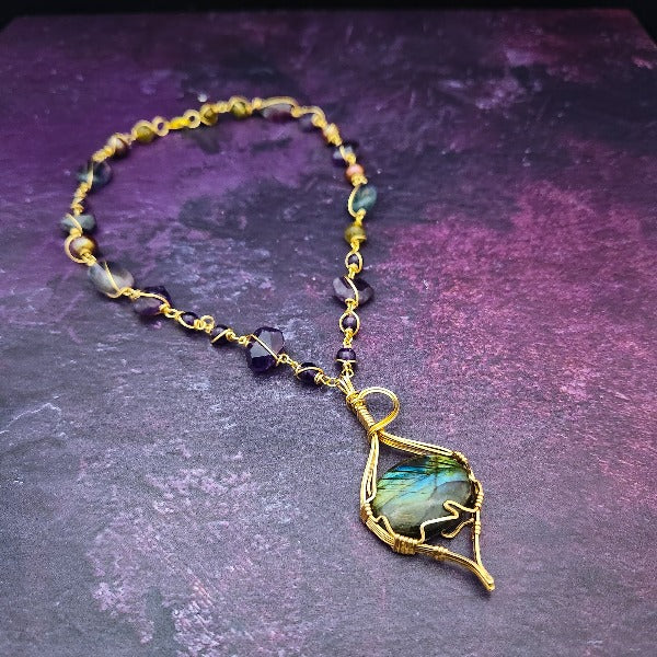 We all have a light within, an inner glow that others may see when they connect with our spirit. The shimmer and glow of this Labradorite Cabochon reminds me of this. This asymmetrical collar necklace is a testament to artisan craftsmanship and design. The Labradorite Cabochon is encased in a 14K Yellow Gold-Filled Wire Wrapped setting with a beautifully fluid look, and gold-wrapped pieces add a unique look.
