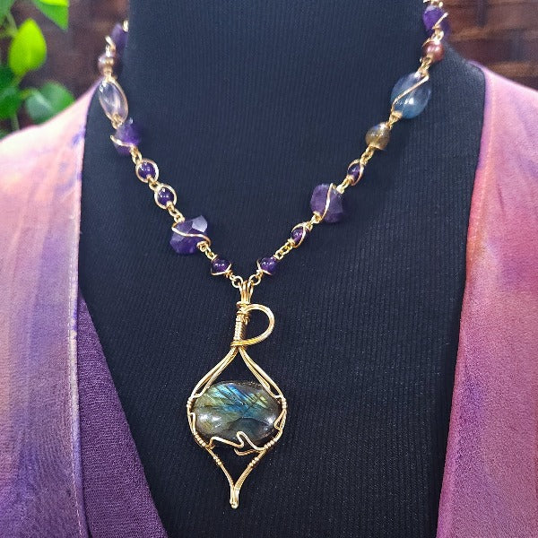 We all have a light within, an inner glow that others may see when they connect with our spirit. The shimmer and glow of this Labradorite Cabochon reminds me of this. This asymmetrical collar necklace is a testament to artisan craftsmanship and design. The Labradorite Cabochon is encased in a 14K Yellow Gold-Filled Wire Wrapped setting with a beautifully fluid look, and gold-wrapped pieces add a unique look.
