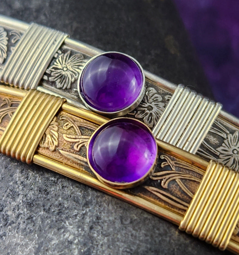 Decorative object with purple gemstones and gold and silver patterns on a dark background