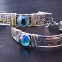 Two silver bracelets with blue gemstones on a dark surface