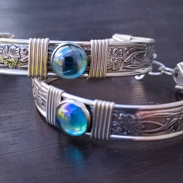 Two silver bracelets with blue gemstones on a dark surface