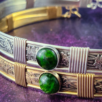 Decorative bracelet with green stones and gold and silver accents on a purple surface