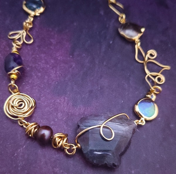 Feel empowered and beautiful wearing our exquisite Zasha Gemstone Collar, meticulously crafted with 14K gold-filled and stunning Amethyst gemstones. The hand-sculpted wire details, reminiscent of delicate flower petals, make this piece truly one of a kind. With a touch of elegance and sophistication, this statement collar will turn heads. 