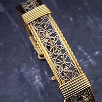 The Dekka Bracelet boasts luxurious open lattice areas of sterling silver with metal accents.