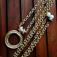 THE 5th AVENUE LARIAT is bold and dramatic, and will definitely get some attention. A large circular disc attached to gold Brittanium chain with both wafer and large freshwater pearls. Simply place the circle where you want it, wrap the chain around your neck and slide the ends thru the circle. Voila! Instant Fashionista!
