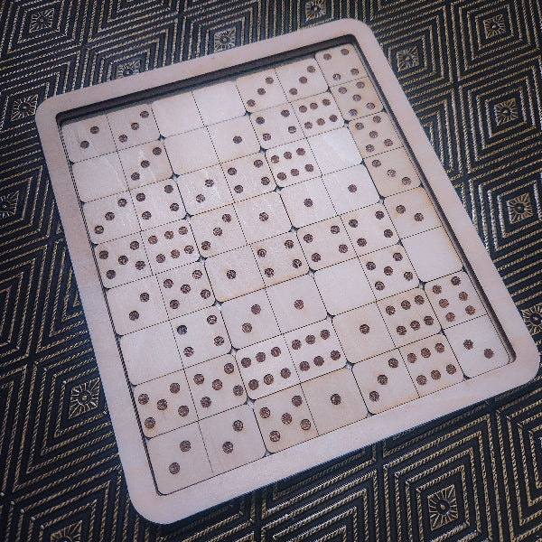 A wooden domino game board with multiple light wood domino tiles arranged on a dark patterned surface.