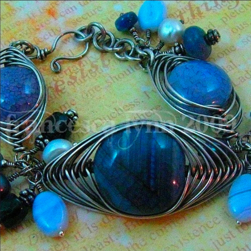Silver wire-wrapped bracelet with blue and white beads on a textured surface