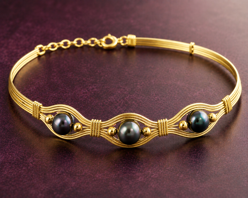 Gold bracelet with black pearls on a dark purple background