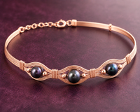 Rose gold bracelet with black beads on a dark purple background