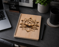 Wooden notebook with lotus design on a desk with laptop and coffee cup.
