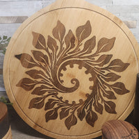 Wooden cutting board with leaf pattern on a wooden surface