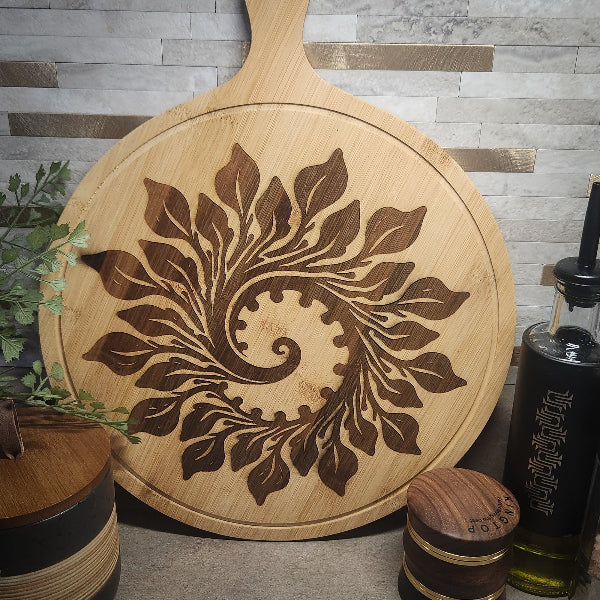 Wooden cutting board with leaf pattern on a gray tiled wall background