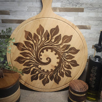 Wooden cutting board with leaf pattern on a gray tiled wall background