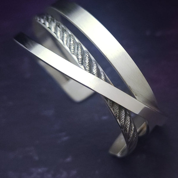 Experience the sophistication of our CROSSOVER Cuff No. 3, featuring smooth sterling silver bands intricately woven to form a unique bracelet. The traditional rope design adds dimension and flair.

Pair it with our collars to make a bold statement.