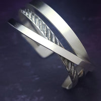 Experience the sophistication of our CROSSOVER Cuff No. 3, featuring smooth sterling silver bands intricately woven to form a unique bracelet. The traditional rope design adds dimension and flair.

Pair it with our collars to make a bold statement.