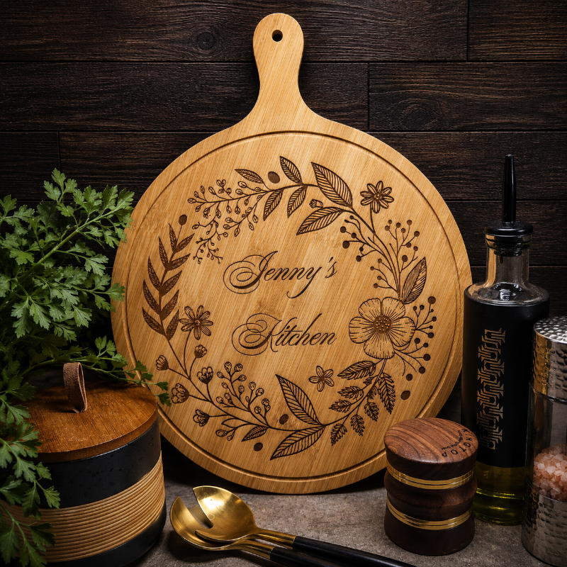 Wooden cutting board with engraved text and floral design, placed on a wooden surface with kitchen items.