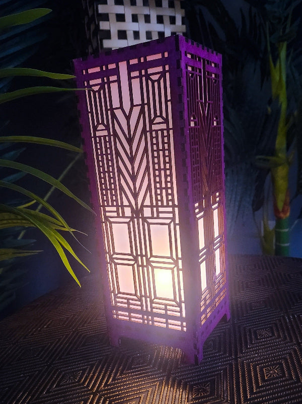 Decorative purple lantern with geometric pattern on a textured surface with plants in the background