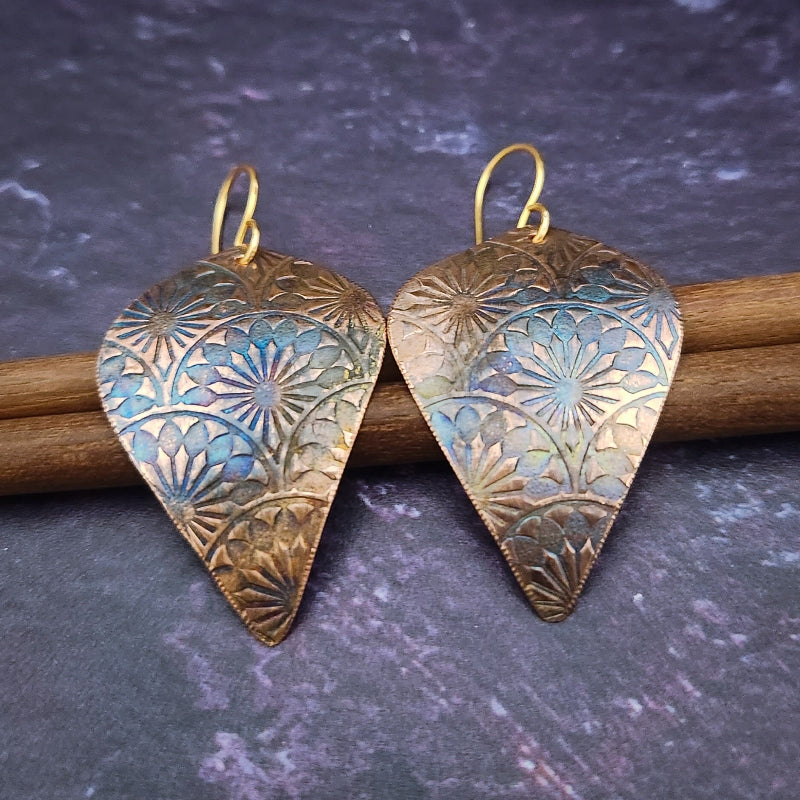 Copper is hand cut and sculpted, then embossed with unique patterns. The pieces are then kissed with a torch to create beautiful, vibrant colors