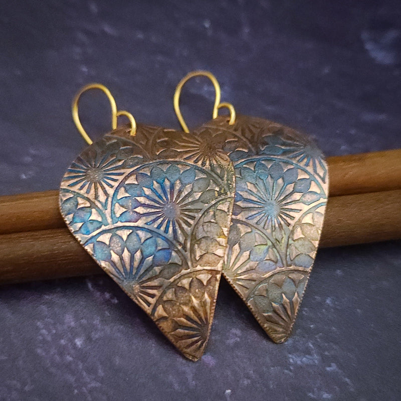Copper is hand cut and sculpted, then embossed with unique patterns. The pieces are then kissed with a torch to create beautiful, vibrant colors