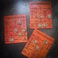 Three orange Tennessee football-themed bingo cards arranged on a dark patterned fabric background.