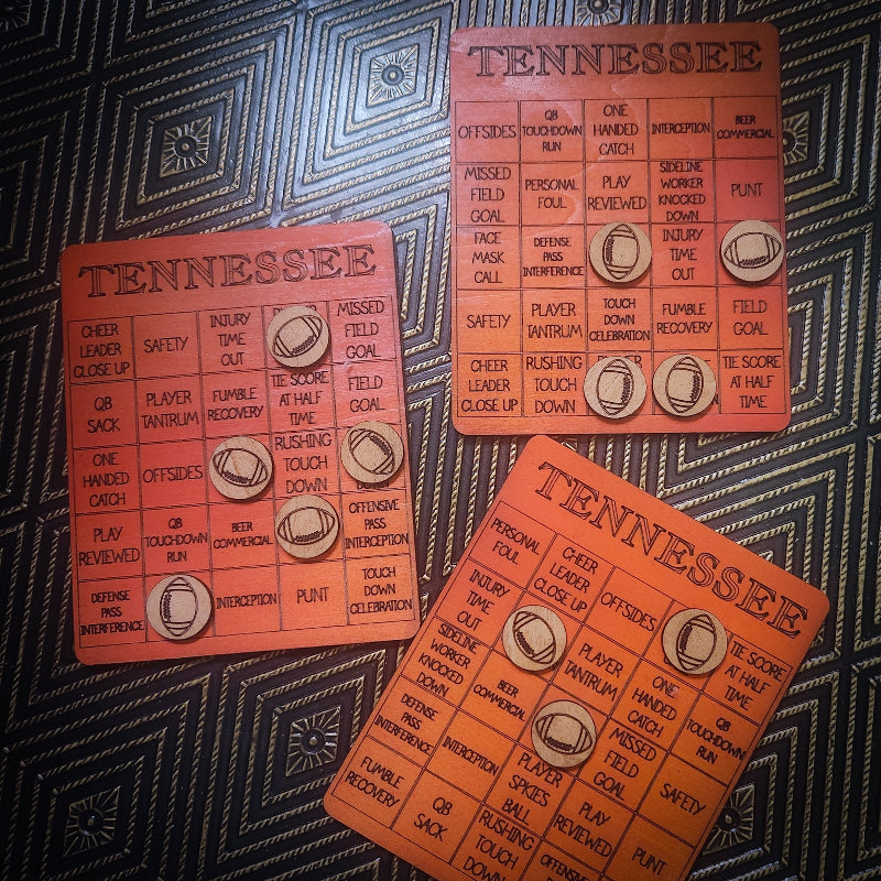 Three orange Tennessee football-themed bingo cards arranged on a dark patterned fabric background.