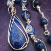 DEEP BLUE like midnight skies and ocean depths.  This asymmetrical collar necklace is a testament to artisan craftsmanship and design. The Lapis Lazuli Cabochon is encased in a Wire Wrapped setting with a beautifully fluid look, And the gemstones are embellished with sterling silver adding a unique look.