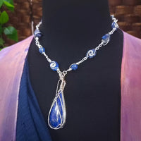 DEEP BLUE like midnight skies and ocean depths.  This asymmetrical collar necklace is a testament to artisan craftsmanship and design. The Lapis Lazuli Cabochon is encased in a Wire Wrapped setting with a beautifully fluid look, And the gemstones are embellished with sterling silver adding a unique look.