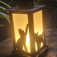 Lantern with cat silhouettes casting a warm glow on a textured surface.