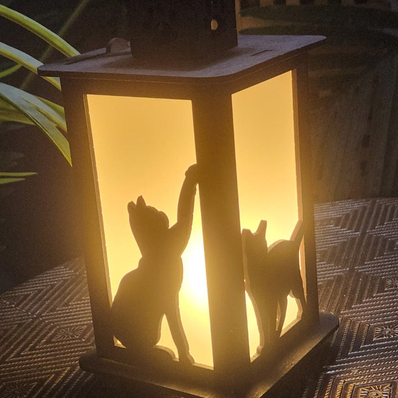 Lantern with cat silhouettes casting a warm glow on a textured surface.