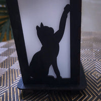Black silhouette of a cat on a white candle with a textured surface below