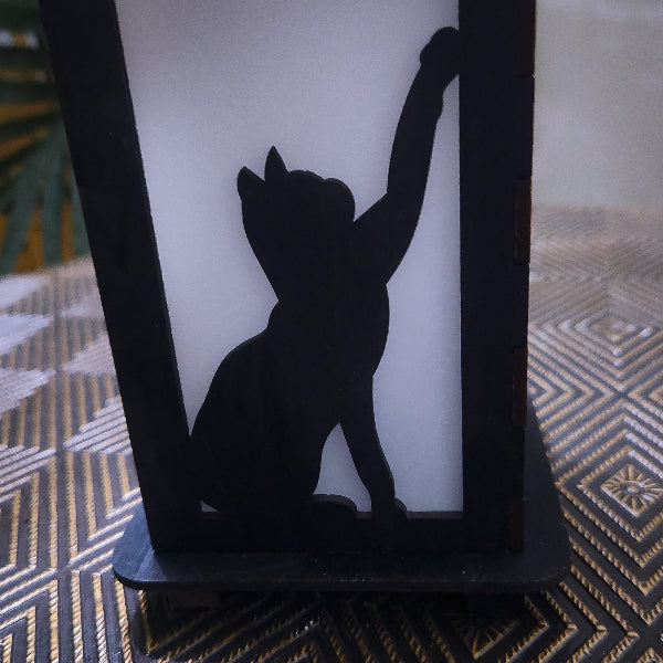 Black silhouette of a cat on a white candle with a textured surface below