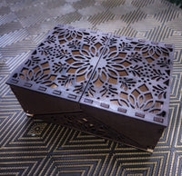 Decorative wooden box with intricate cut-out design on a patterned surface