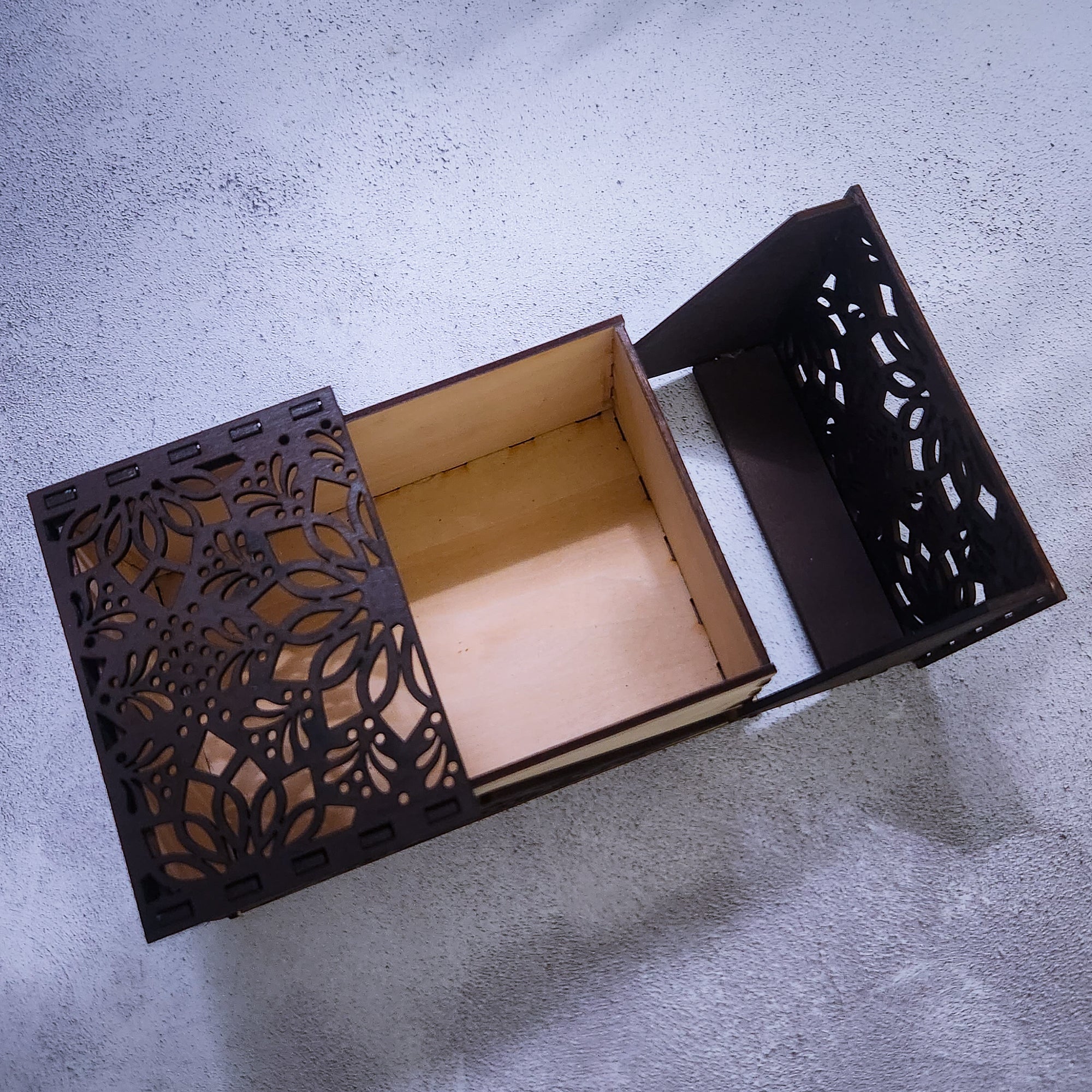 Decorative black box with intricate cut-out patterns on a gray surface