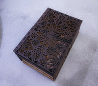 Decorative metal box with intricate cut-out patterns on a gray surface