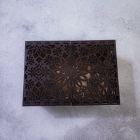 Decorative wooden box with intricate cut-out patterns on a gray surface