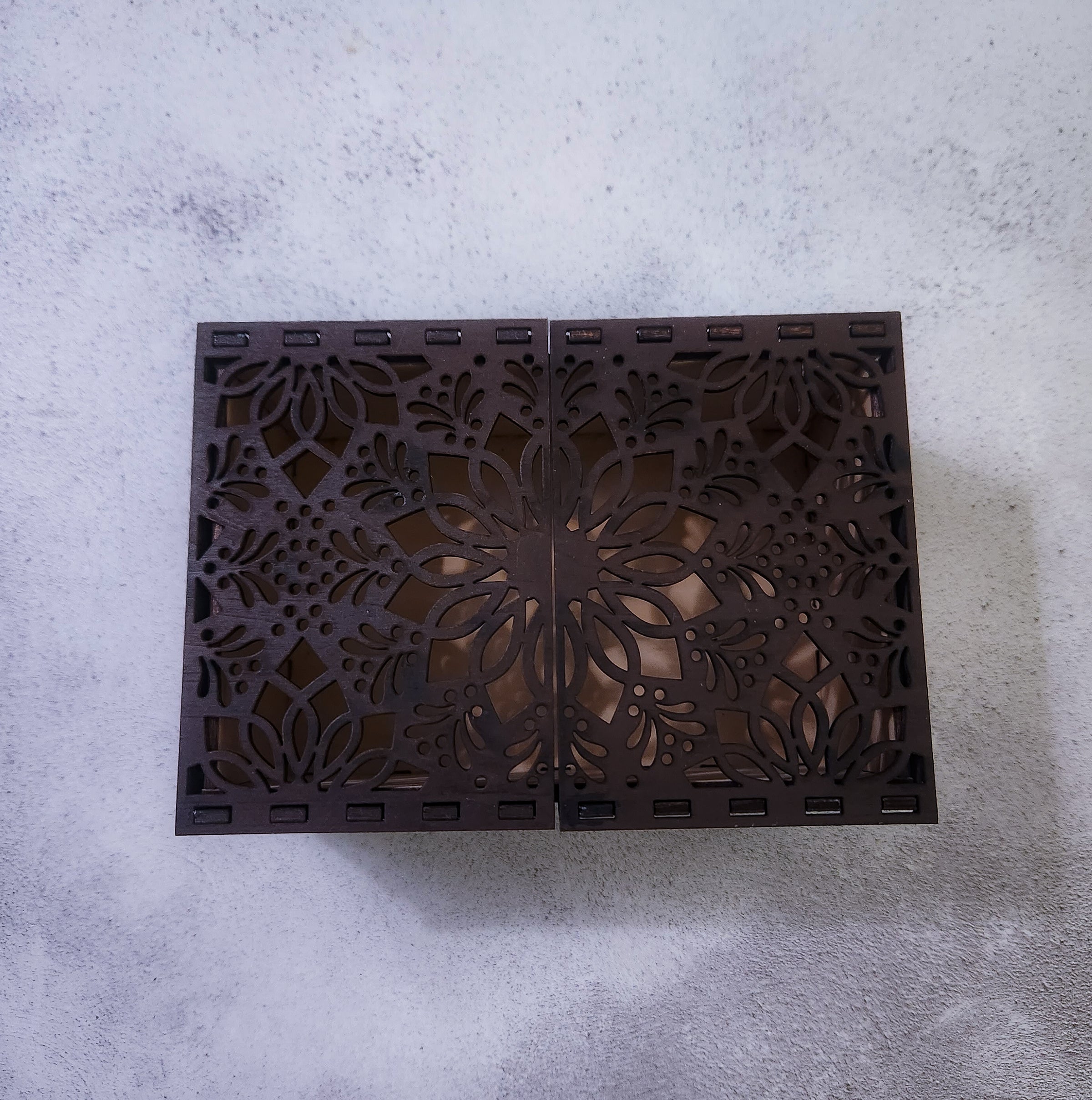 Decorative wooden box with intricate cut-out patterns on a gray surface