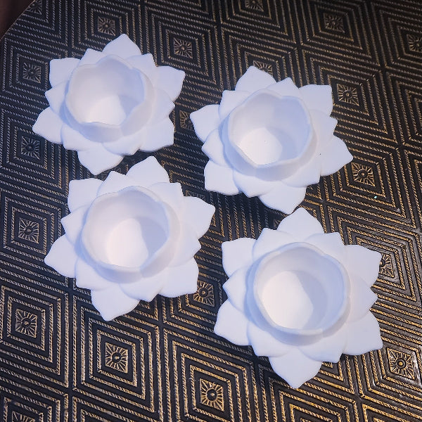 Four white flower-shaped candles on a textured dark surface