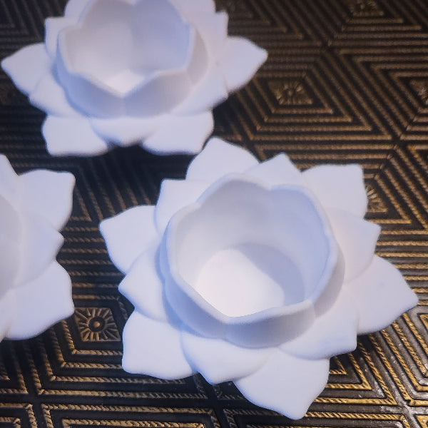White ceramic flower-shaped containers on a textured surface
