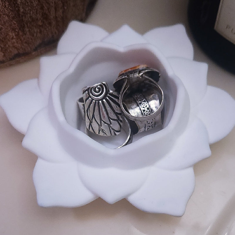 Two silver rings in a white concrete lotus bowl