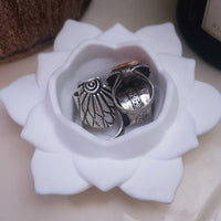 Two silver rings in a white concrete lotus bowl