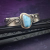 This unique piece features a breathtaking Larimar cabochon and two faceted Amethyst stones, adorned with intricate handcrafted waves. The gemstone is carefully set in a handcrafted sterling silver bezel, making it a true one-of-a-kind design. All Sterling Silver.