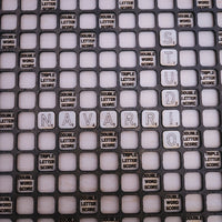 A close-up of a black Scrabble-style tile grid with white square tiles spelling out 'NAVARRIO' and many score tiles such as 'DOUBLE LETTER SCORE' and 'TRIPLE LETTER SCORE'.